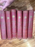 Six red Encyclopedia of Canada volumes standing, gilt maple leaf on spines visible.