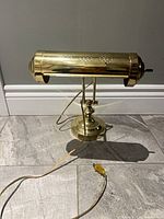 Front view of brass-tone adjustable bankers lamp showing cylindrical shade and base