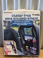 Front of sealed retail box showing Merkury Innovations clutter free auto back seat organizer