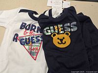 White and navy bodysuits laid out showing graphics and logos