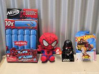 Group shot showing all four items: Nerf dart pack, Spider-Man plush, Darth Vader figure, Hot Wheels car
