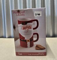 Front of sealed box showing stacked Santa mugs