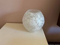 Frosted glass floral globe lamp unlit on tabletop