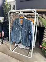 Front view of white metal garment rack with assorted hangers