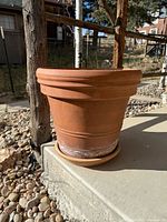 Side view of large terracotta planter on saucer showing overall shape and mineral residue