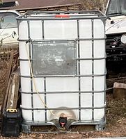 Front view of white plastic IBC tank with metal cage, bottom valve and top cap visible