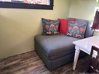 Sofa bed in seating position against wall, decorative pillows on top