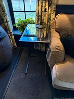 Full view of steel frame glass-top side table beside sofa