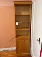 Full view tall pine bookshelf with cabinet door closed