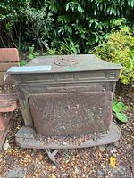 Full view of cast iron stove with mesh front door outdoors