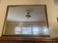 Front view of rectangular gold-tone framed mirror on mantle