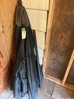 Closed patio umbrella leaning against wall showing full length and canopy