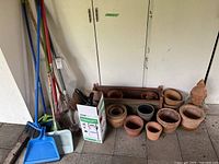 Group view of pots, sprayer box, yard tools leaned against wall