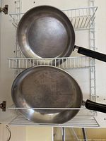 Two stainless steel fry pans on wire rack
