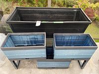 Front view of large black planter and stand with three blue planters