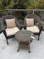 two rattan armchairs with cushions and side table