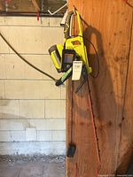 Full view of hedge trimmer hanging on wall with battery attached and charger below