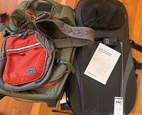 All three items laid out: Osprey backpack, Eddie Bauer suitcase, Snailax seat massager with adapter and manual