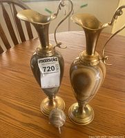 Two stone and brass ewers with stone egg on table