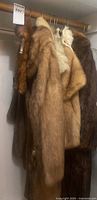 All three fur coats hanging on closet rod