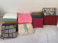 Group shot of all blankets and pillows lined against wall