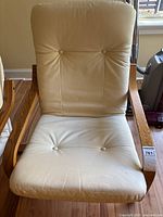 Front view of chair showing cream leather cushions and wood frame