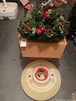 Wreath on box, tree stand on floor, some wrap rolls visible