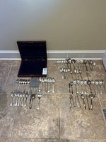 Entire lot laid out showing storage chest, Community Plate place settings and assorted extra pieces