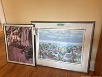 Both framed artworks standing against wall