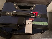 Top of navy suitcase showing handle and size tag