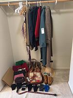 Overall lot view: coats on rod, scarves, purses, gloves, boots, sun hat, hockey stick