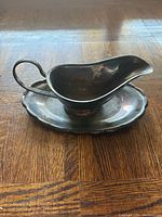 Gravy boat on matching underplate showing overall design and patina
