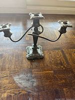 Front view of silverplate three-arm candelabra showing twisted arms, three sockets, and ornate base