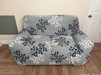 Front view of loveseat fitted with grey floral slipcover