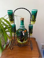 Front view of bottle in rack with four of six shot glasses visible