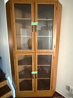 Full view of wooden corner china cabinet showing glass doors and shelving