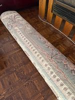 Rolled wool rug showing floral border and pile