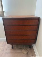 Front view of the 5-drawer wooden dresser showing finish, drawers, and legs
