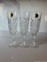 Front view of three Cristal D'Arques Palais crystal champagne flutes with stickers visible