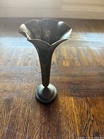 Full view of copper bud vase standing on wood floor