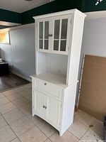 Full view of white buffet hutch showing upper glass-door cabinet, open shelf, lower drawer and cabinet