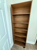 Front view of tall wooden shelving unit showing six shelves and overall wear