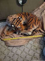 Full view of plush tiger curled on blanket