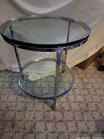 Full view of round chrome frame table showing glass top and lower shelf