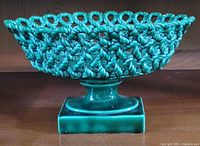 Side view of green braided ceramic pedestal bowl on square base