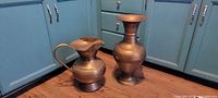 Front view of brass pitcher and vase side by side