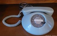 Front view of mint green rotary telephone showing handset on cradle and rotary dial
