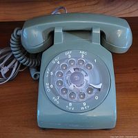 Full view of green rotary phone with handset on cradle