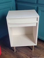 Front view of white wooden end table with drawer and open shelf