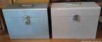 Front view of both metal file boxes closed showing handles and latches
